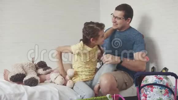 小爸爸和小女儿一起在孩子们房间里玩女孩拥抱她父亲视频的预览图
