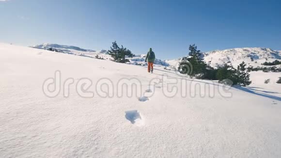 女孩在冬天的山上徒步旅行脚印在雪地里慢动作视频的预览图