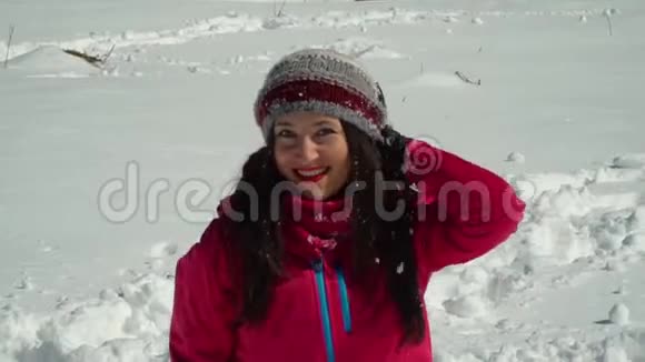 快乐的年轻女子在玩扔雪她在笑一个女孩在冬日的森林里漫步视频的预览图