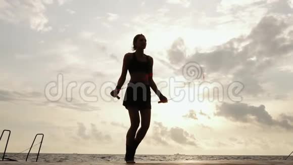 无法辨认的运动女性在海滩边的阳光下在跳绳上慢动作一个女孩在跳视频的预览图