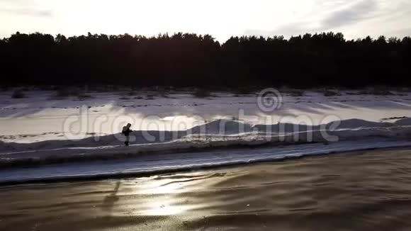 空中飞行在冰冻的海滨覆盖着雪其中一个人正沿着它走视频的预览图