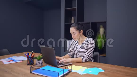 在办公室内部使用笔记本电脑的年轻成功女商人视频的预览图