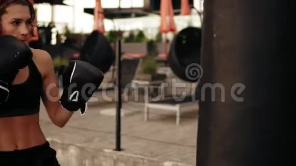 年轻的女拳击手戴手套用手和肘部踢拳击袋在外面健身女拳击手视频的预览图