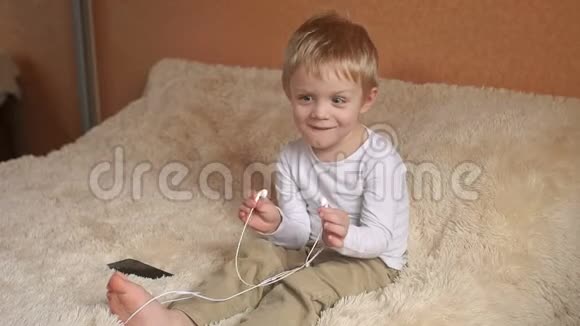 快乐的小男孩在卧室里听音乐视频的预览图