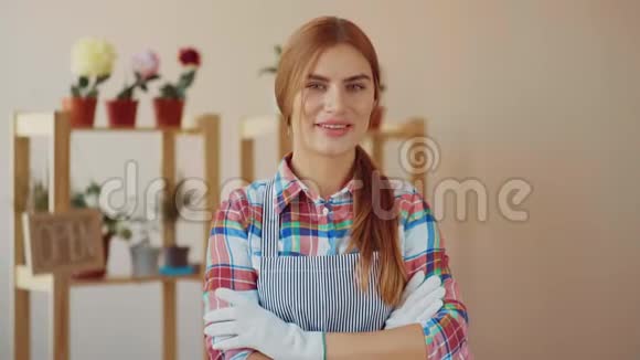 小生意一个穿着条纹围裙和格子衬衫的女孩站在一家花店里花店女站在附近视频的预览图