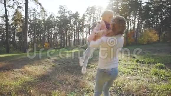 一位年轻的母亲在一个秋天的公园里旋转她的孩子女孩们在森林里玩耍视频的预览图