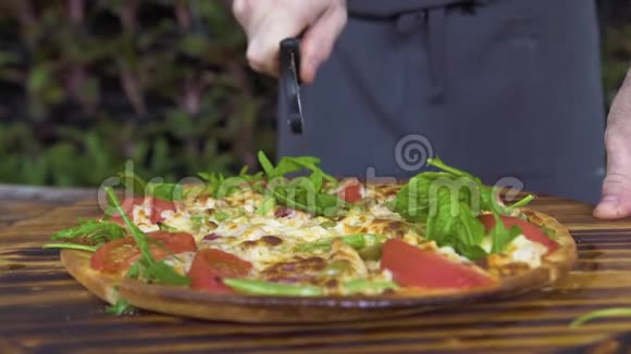 在披萨店的木桌上用滚刀将披萨切好厨师切意大利热比萨饼视频的预览图