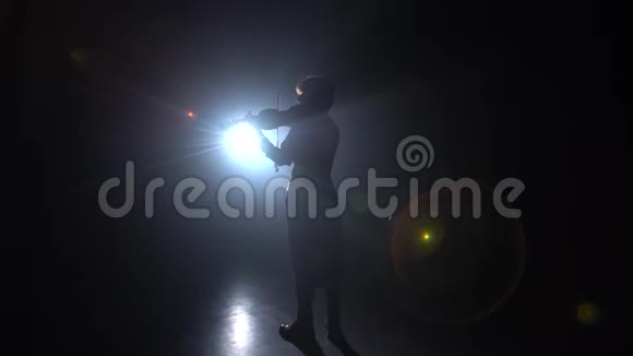 音乐家女孩背对着相机拉小提琴黑烟背景背面视频的预览图