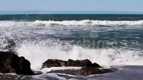 海浪冲击沙滩冲浪者的岩石背景视频的预览图