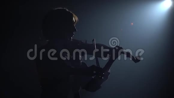 黑暗工作室灯笼女孩拉小提琴剪影黑烟背景视频的预览图