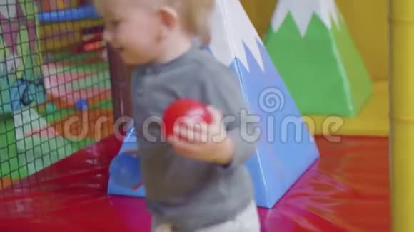 金发幼儿尝试通过玩具围栏背面视频的预览图