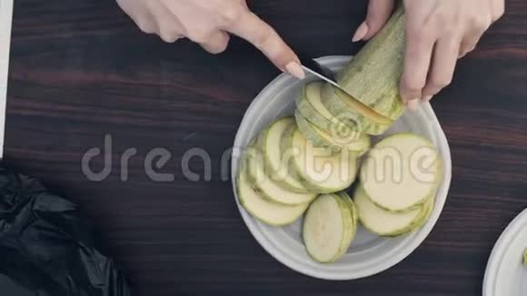 女性用刀切手切菜髓在桌上的盘子里视频的预览图