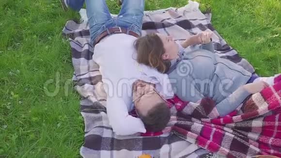 躺在草地上的父母孩子们在公园里玩得很开心也有跑步的背景视频的预览图