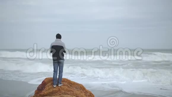 在暴风雨中年轻人在寒冷的海滩上放松视频的预览图
