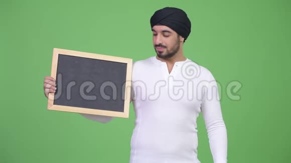 年轻快乐的留着胡子的印度男人在黑板上竖起大拇指视频的预览图