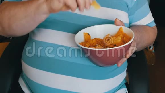 胖懒汉正坐在椅子上吃薯片一个穿着条纹T恤的男人的大肚子不是快餐视频的预览图