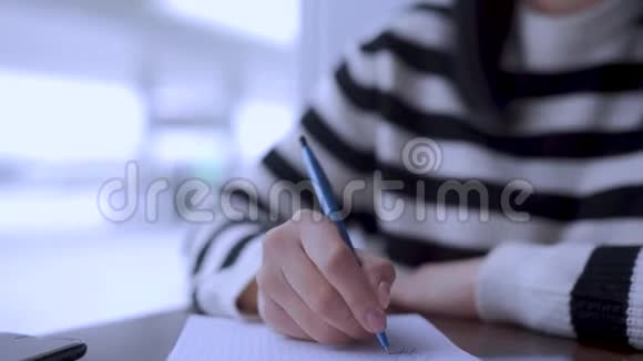 年轻女子写在笔记本上想着并梦想着美好的事物视频的预览图