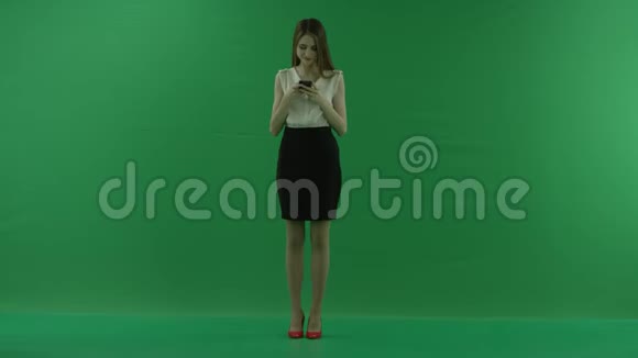 一位身穿白衬衫黑裙的年轻商务女性正在用手机侧着身子站在绿色的旁边视频的预览图