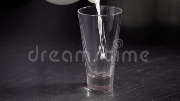 一杯新鲜牛奶倒在黑桌上的特写镜头视频的预览图