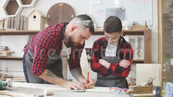 在木工工作室孩子们和年轻人可以和爸爸一起学习一个有用的职业视频的预览图