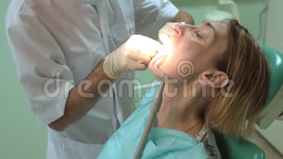 牙医在牙科诊所治疗一颗美丽的女性病人的牙齿视频的预览图