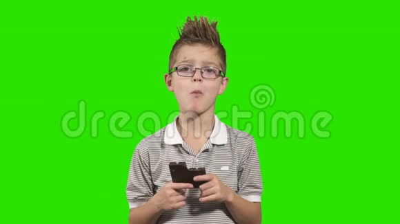可爱的男孩吃巧克力显示拇指和绿色背景视频的预览图