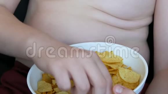 肥胖的少年身体上有脂肪褶皱正在吃薯片不健康食品快餐儿童营养问题视频的预览图