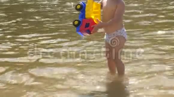 夏天小男孩在河边玩玩具车视频的预览图