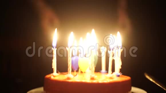 美丽的黑发年轻女子许愿在生日巧克力蛋糕上吹蜡烛中镜头视频的预览图