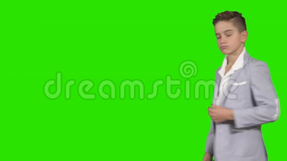 穿西装的小男孩在绿色背景下戴上可怕的面具视频的预览图