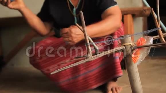 当地的卡伦斯加夫山区部落的一名妇女在准备手工编织传统服装和CRA时滚动一个蓝色染色线球视频的预览图
