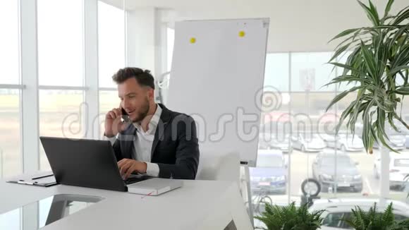 在智能手机上与商务中心的工作场所愉快的高管交谈在现代办公室与年轻老板的电话交谈视频的预览图