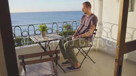 一个男人在海边的阳台上喝酒视频的预览图