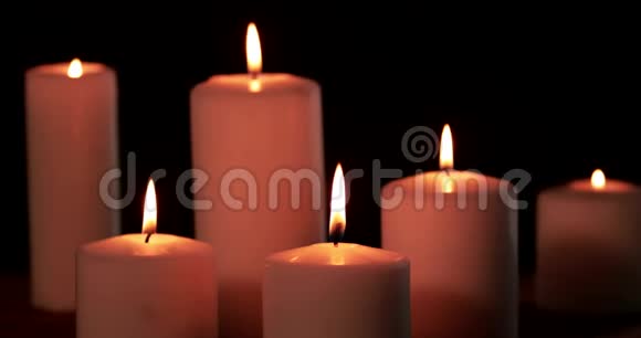 六支白色圣诞蜡烛在黑暗中燃烧视频的预览图