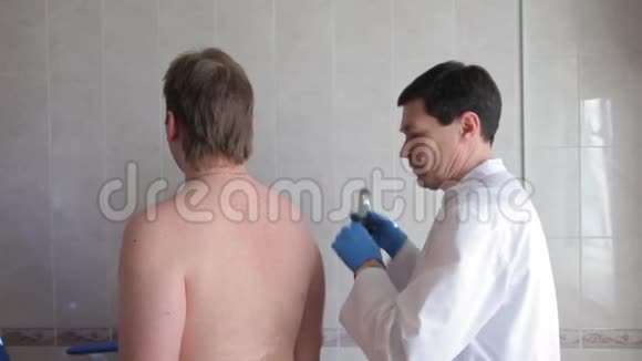 一位男性医生用电子医疗设备检查病人皮肤医疗技术视频的预览图