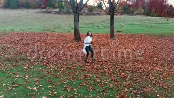 年轻漂亮的女孩在秋天的森林里玩得很开心她拿着一束黄叶她跑过去看着视频的预览图