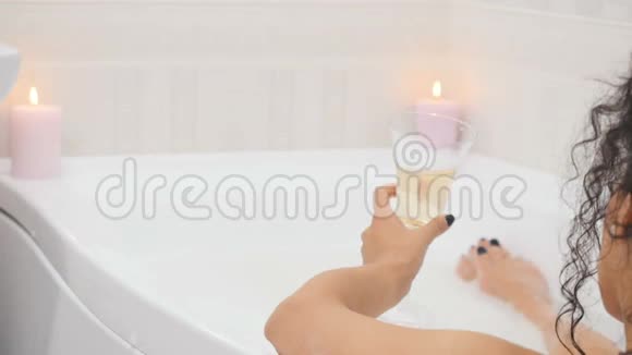 美女用泡沫和蜡烛洗澡喝香槟视频的预览图