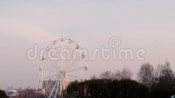 摩天轮在冬季公园的城市背景粉红色的日落天空视频的预览图