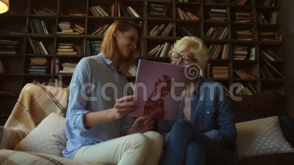 积极向上的高级妇女和她的女儿在看时装杂志视频的预览图