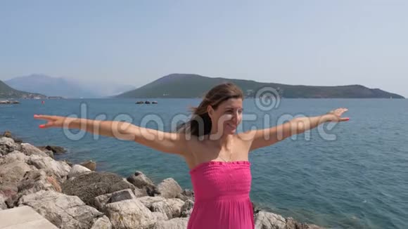 穿着粉色衣服的快乐女人抬起手臂向侧面慢动作4K视频的预览图