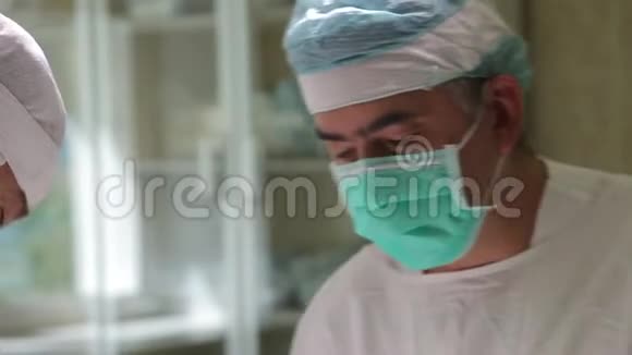 特写镜头两名外科医生穿着防护服进行肿瘤外科手术视频的预览图