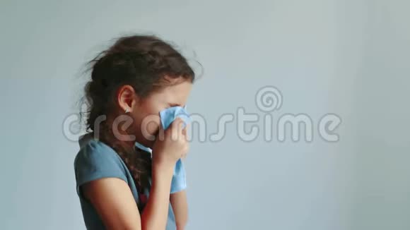 女孩在灰色背景上打喷嚏成手帕小女孩感冒了吹鼻子少女感冒视频的预览图