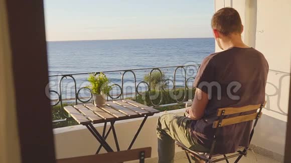一个男人在海边的阳台上喝酒视频的预览图