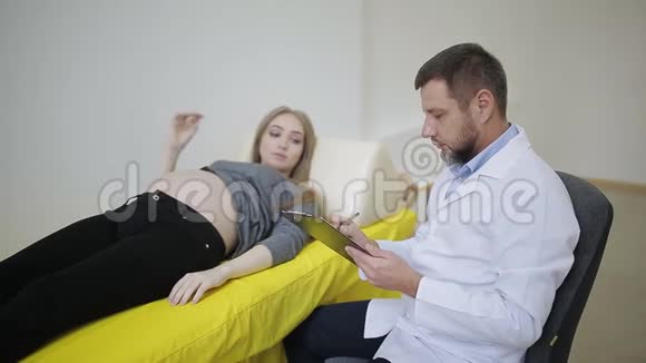 医生把手放在孕妇肚子上怀孕妇女医疗卡上的条目视频的预览图