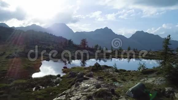 在日落的夏日在清澈的蓝色湖泊和帐篷营地之上前进欧洲意大利阿尔卑斯山山谷奥斯塔户外绿色视频的预览图