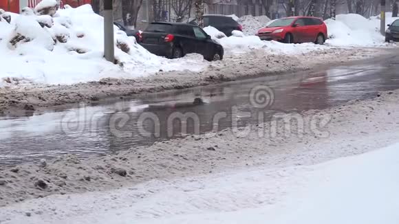 大雪纷飞的城市里车流如潮的汽车在路上穿过一个水坑视频的预览图
