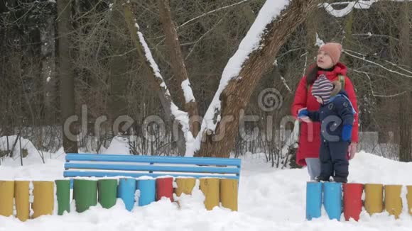 可爱的小男孩和年轻的母亲在冬天和公园里的雪玩耍蓝色的孩子夹克和红色的妈妈视频的预览图