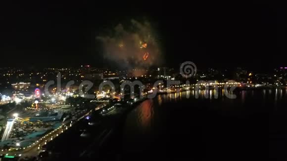 晚上在海岸的一个小镇上燃放节日烟火鸟瞰城市大海和烟花视频的预览图