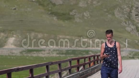 年轻英俊的男人走在山里一个人在山上的背景下打电话一个男人视频的预览图