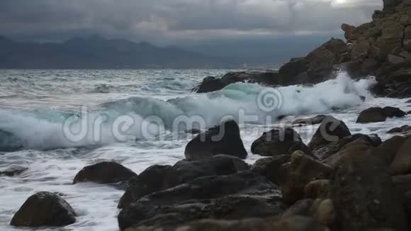 海浪拍打着石头海岸的雨滴的缓慢运动视频的预览图